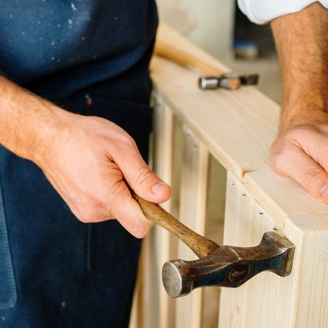 A craftsman assembling a pine and spruce wooden frame by hand